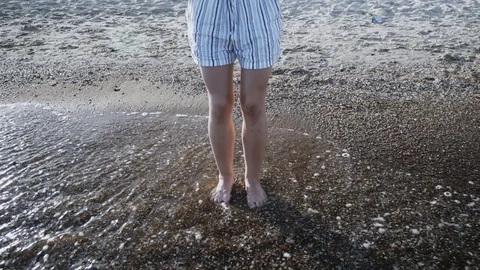Woman's legs makes small jumps in the sea water at sunset. Close-up, female l Stock-Footage 115029987