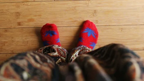 Woman's legs moving in red socks with marijuana print on wooden floor top view 스톡 동영상 89773378