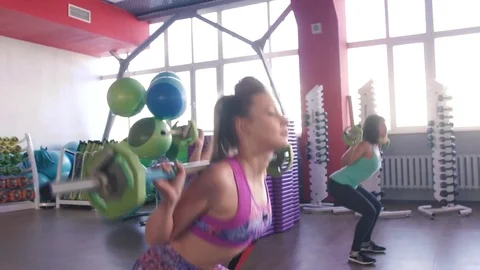 Womans with muscular arms pulling up large barbell in fitness training class Stock-Footage 75869728