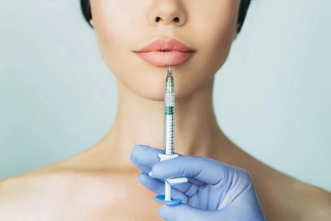 Woman's plumper lips, getting bigger lips. prick of a syringe for the lips... Stock Photos