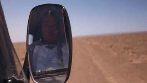 Woman's reflection in a car mirror driving through a desert Stock-Footage 343318085