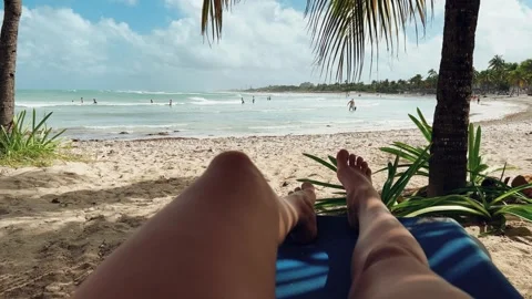 A woman's rest under a palm tree on the ocean shore.  Stock Footage 269160496