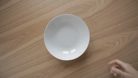 Woman's right hand take off plain empty white plate from wooden table TOP VIEW Vidéo 115091948
