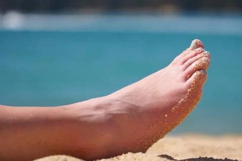 Woman's sandy foot on beach Stock Photos