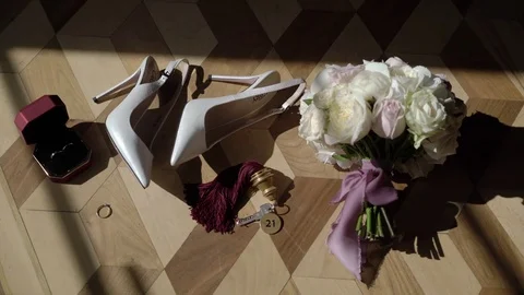 Woman's shoes on heels, bouquet, wedding rings and keys from room Stock Footage