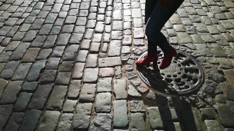 A woman's silhouette  crossing a cobblestone road on a sunny day in slow motion. Stock Footage