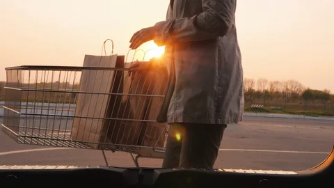 Woman's silhouette, opens the trunk of a car, puts there paper shopping bags Stock Footage 107141600