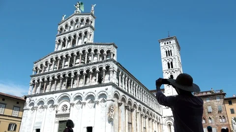 Woman's silhouette with straw hat taking picture of San Michele in Foro, Lucca Stock Footage 94396089