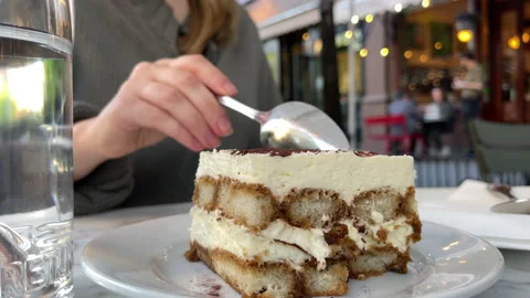 Woman's spoon digs into cake dessert at outdoor dining in New York City Stock Footage 195740478