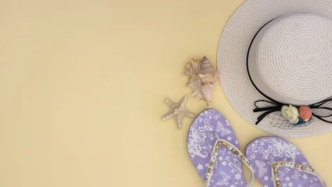 Woman's white hat and slippers and sea shells on yellow background - Stop motion Stock Footage 108069341