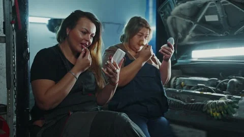 Women applying makeup while working in a garage during the afternoon Stock Footage 305848981