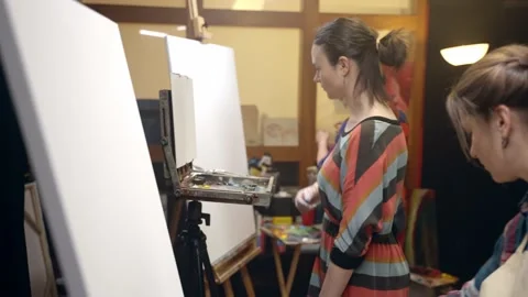 Women artists approaching the easel with paints and brushes to start painting. Stock Footage
