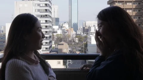 Women chatting on a veranda with a city view. Stock Footage