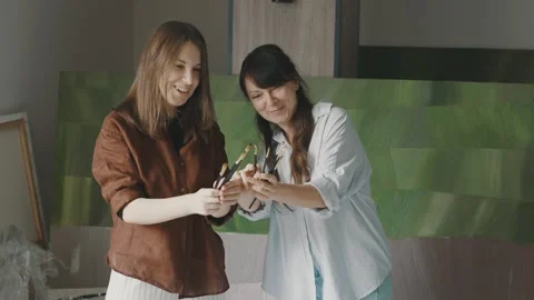 Women create art together in a spacious studio filled with colorful paintings Video stock 322059622