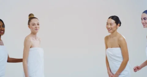 Women of different ethnicities in white bathing towels are laughing in camera. Stock Footage 114687926