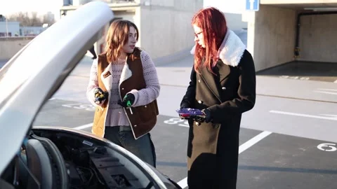 Women discuss car engine problem holding tools near hood 库存影片 332871955
