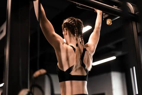 Women doing pull ups training arms in the gym. Upper body training. Stock Photos