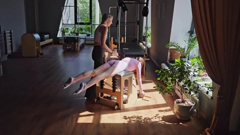 Women doing Swan exercise on Pilates Chair for the chest and back muscles Stock Footage 346285234