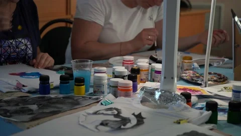 Women draw on sheets of paper while sitting at a table in dim light. moscow Stock Footage 159828431
