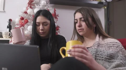 Women drinking coffee and using laptop at home at Christmas Stock Footage 133375473