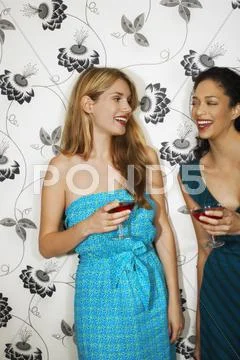 Women Drinking Martinis Against Floral Print Wall Stock Photos