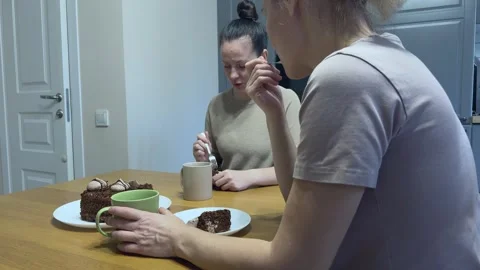Women Drinking Tea With Chocolate Cake Talking And Smiling Cozy Home Scene Stock Footage 344248345