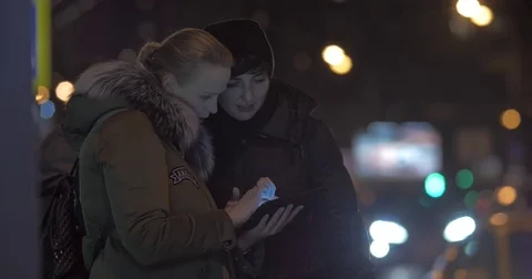 Women friends using tablet PC when waiting for bus in the street Stock Footage 81375220