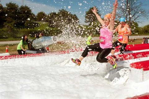 Women get sprayed with bubbles jumping into foam pit Stock Photos