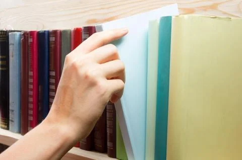 Women Hand selecting book from a bookshelf in library. Back to school Photos