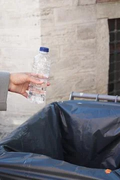 Women hand throwing an empty plastic water bottle in the garbage trash or bin Stock Photos
