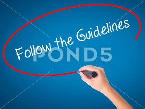 Women Hand writing Follow the Guidelines with black marker on v Stock Photos