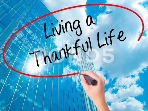 Women Hand writing Living a Thankful Life with black marker on v Stock Photos