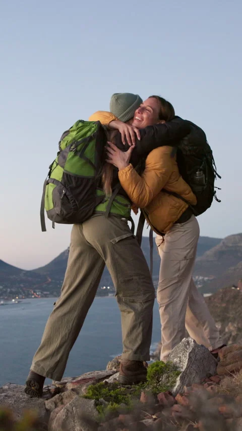Women, hiking and high five on mountain with hug, sea view or achievement for Stock Footage 332829132