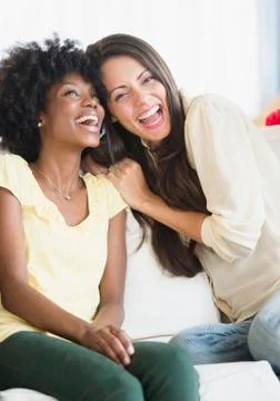 Women laughing together on sofa Stock Photos