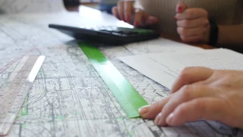 Women looking at map counting cost of work on calculator. Video stock 257078722