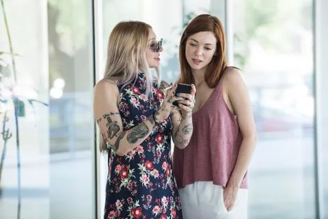 Women looking at smartphone while taking a smoke break Stock Photos