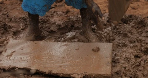Women make Bricks from adobe pressing wet mud mixture into timber frame Stock Footage 109139533