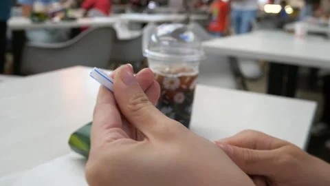 A women opens a package of drinking straws in a cafe or food court. Vídeo Stock 280343442