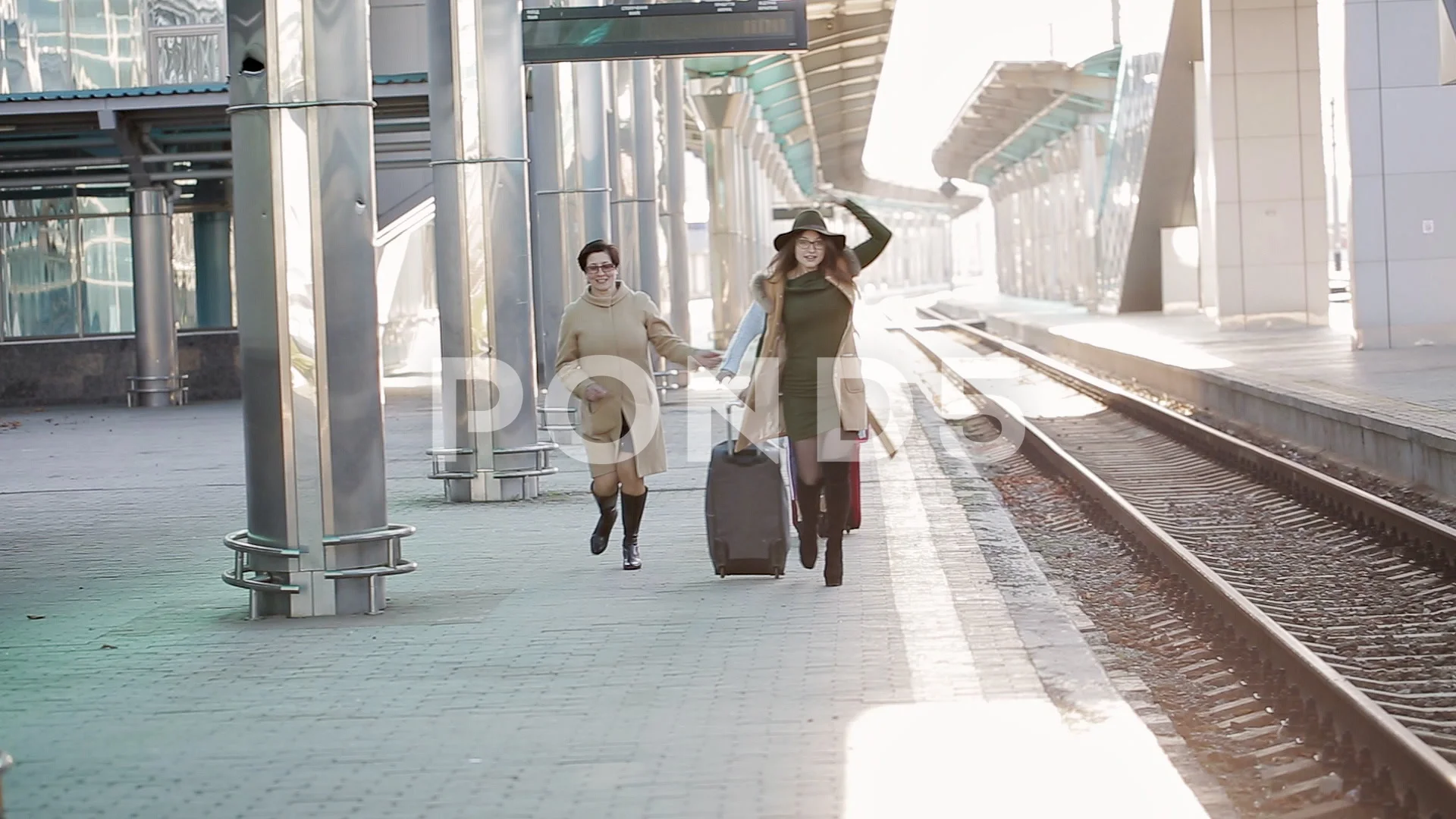 Women passengers running to catch the train before it leaves the railway  station