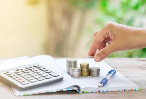 Women paste Coins on stack, calculator, pen and saving account book Stock Photos