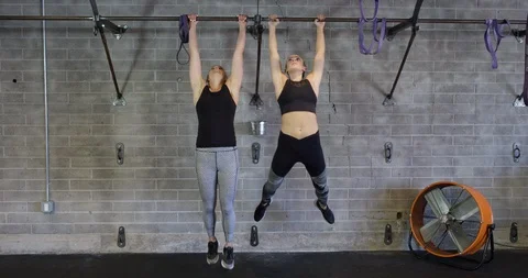 Women perform abs workout on the pull up bar in gym Stock Footage 97356696