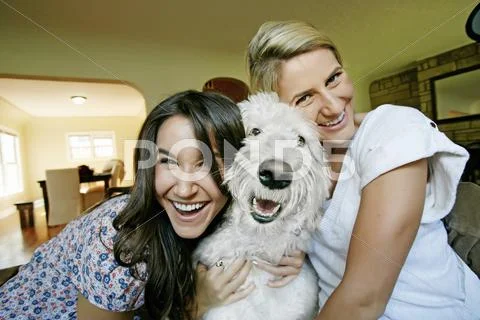 Women petting dog in kitchen Stock-Fotos