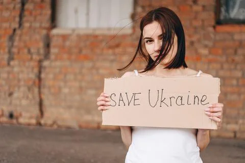 Women with Poster Save Ukraine. A woman with a belligerent look looks into th Stock Photos