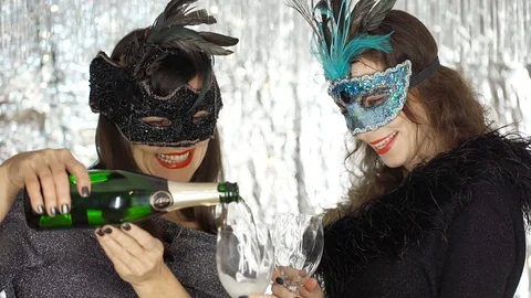 Women pouring champagne to the glasses and enjoying the masquerade party, steady Stock Footage