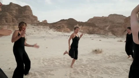 Women practice ecstatic dance in desert. Dynamic active camera movement Stock Footage 130793079