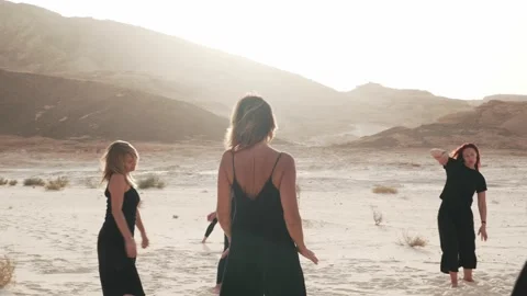 Women practice ecstatic dance in windy weather in desert at sunrise Stock Footage 130786590