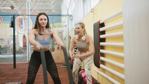 Women practicing workout routines using battle ropes in a gym environment during Stock Footage 344888432