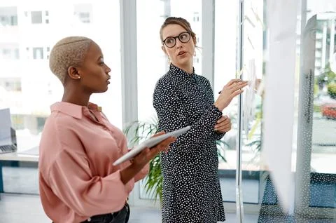 Women, problem solving or brainstorming on glass wall, tablet or sticky note for Foto stock