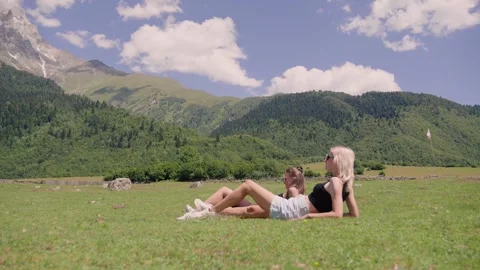 Women relaxing lying down on grass in mountain meadow Stock Footage 301403004