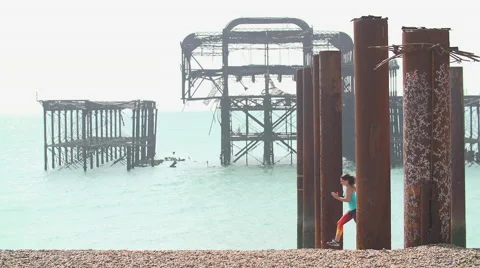 Women Running On Beach With Broken Down Pier in Sea. Vídeo Stock 52728089